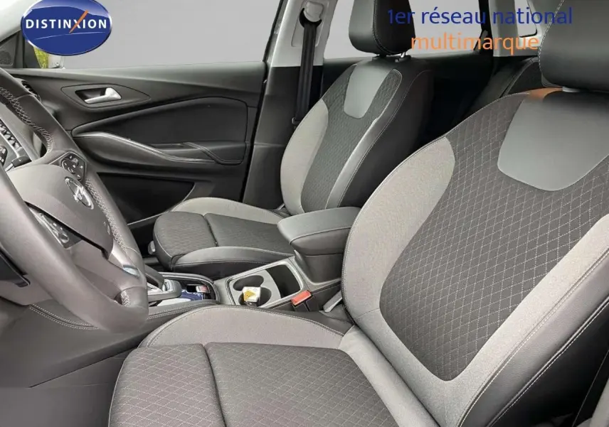 Vue intérieure côté gauche de l’Opel Grandland X 1.6 Hybrid Turbo 2021 avec sièges tissu noir et gris à motifs losanges.