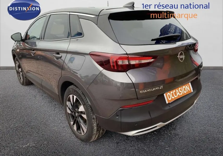 Vue 3/4 arrière droite d’un Opel Grandland X gris Pierre de Lune métallisé avec jantes bi-ton et feux arrière LED.
