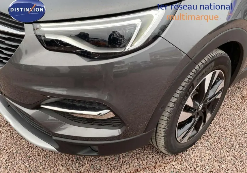 Gros plan sur l'avant droit de l'Opel Grandland X gris Pierre de Lune, mettant en valeur le phare LED et la roue alliage.