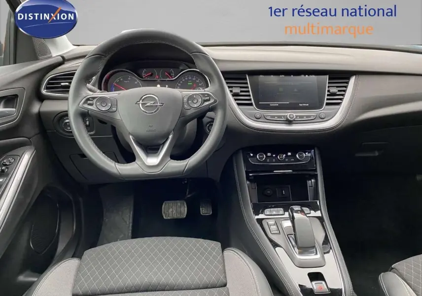 Vue intérieure centrée sur le volant et la console centrale d’un Opel Grandland X 1.6 Hybrid Turbo 2021 en finition noire.