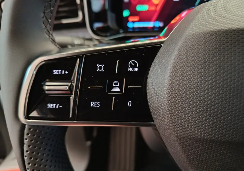 Gros plan sur les commandes de régulateur de vitesse au volant de la Renault R5 Techno 150 ch blanc, intérieur moderne.