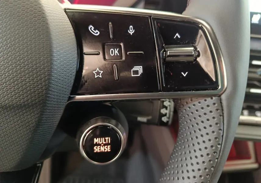 Gros plan sur le volant noir perforé de la Renault R5 Techno 150 ch, avec commandes multifonctions et bouton Multi Sense.