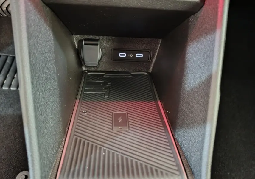 Gros plan intérieur sur la zone de recharge par induction noire avec prises USB et prise 12V dans une Renault R5 blanche 2025.
