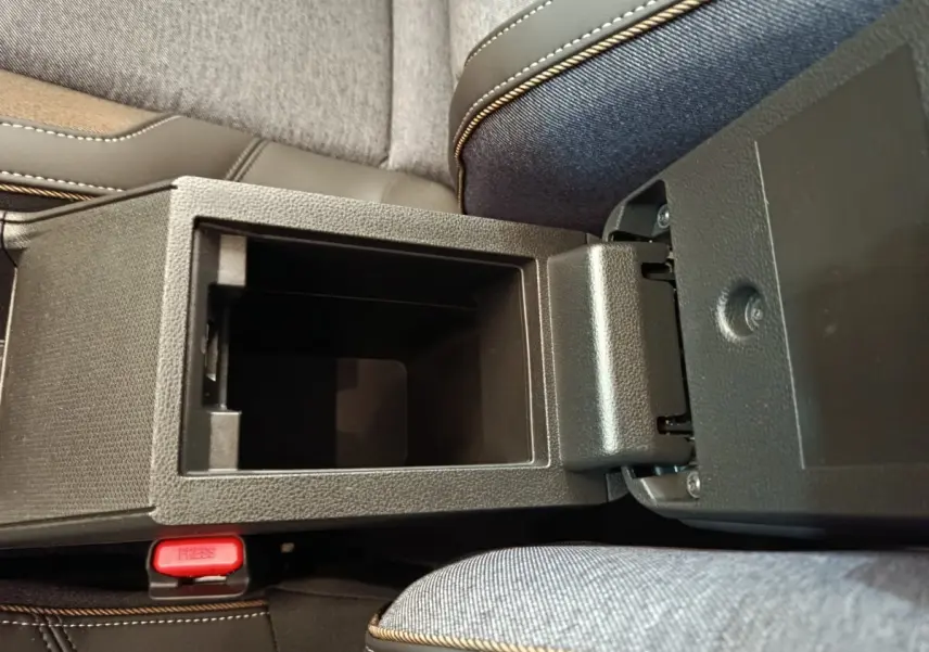 Vue plongeante sur la console centrale ouverte de la Renault R5 Techno 150 ch blanc, avec accoudoir et siège tissu gris.