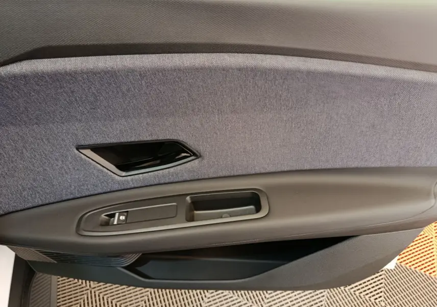 Gros plan sur la garniture intérieure de porte côté conducteur de la Renault R5 Techno blanche, tissu gris et plastique noir.