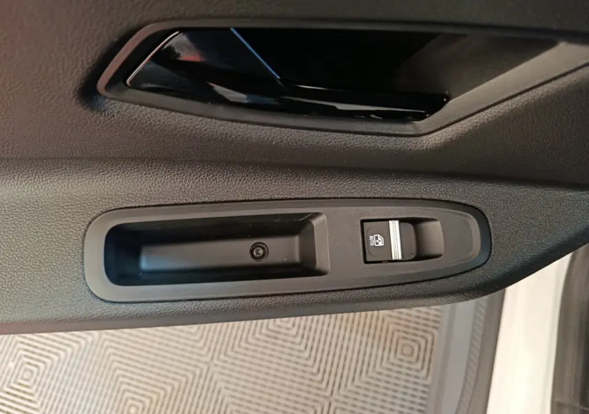 Gros plan sur la commande de lève-vitre côté conducteur d’une Renault R5 Techno blanche, intérieur noir.