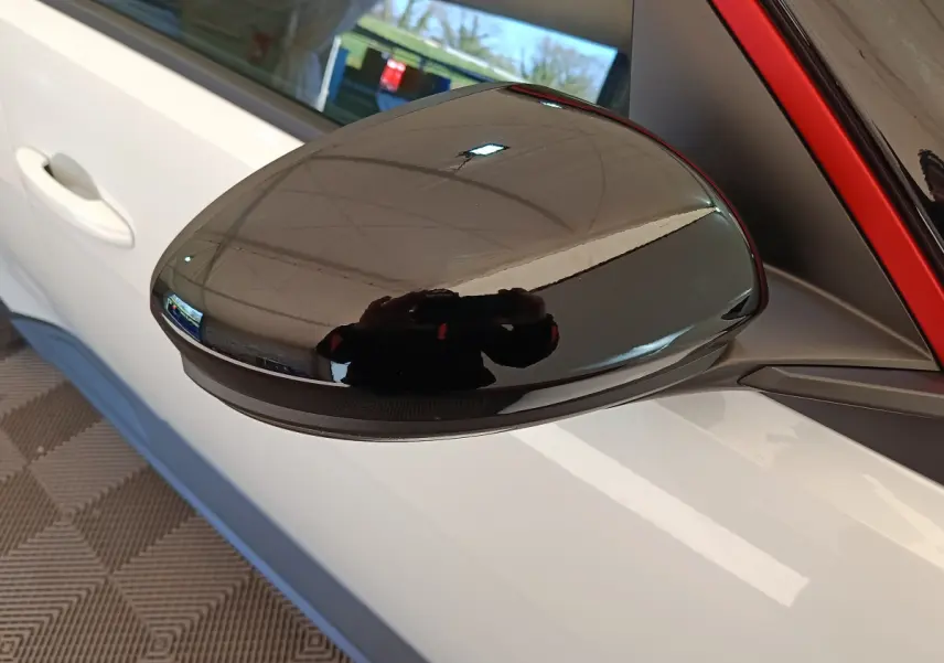 Rétroviseur extérieur noir en gros plan sur côté gauche d’une Renault R5 blanche 2025 électrique.