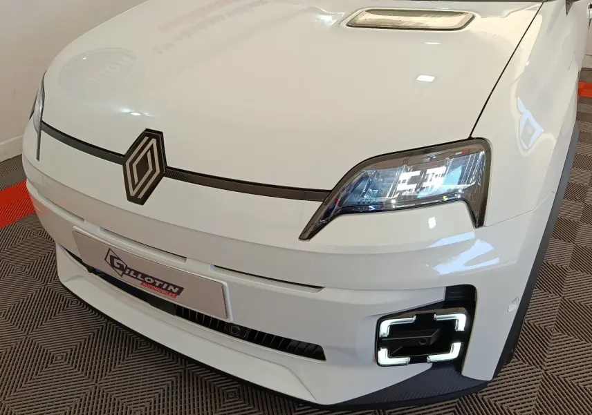 Vue 3/4 avant droit de la Renault R5 Techno blanche 2025 avec phares LED et signature lumineuse carrée distinctive.