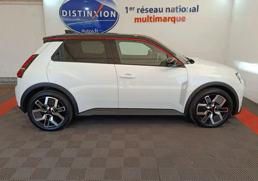 Vue de profil côté gauche d'une Renault R5 Techno électrique blanche avec toit noir et jantes stylisées en concession.