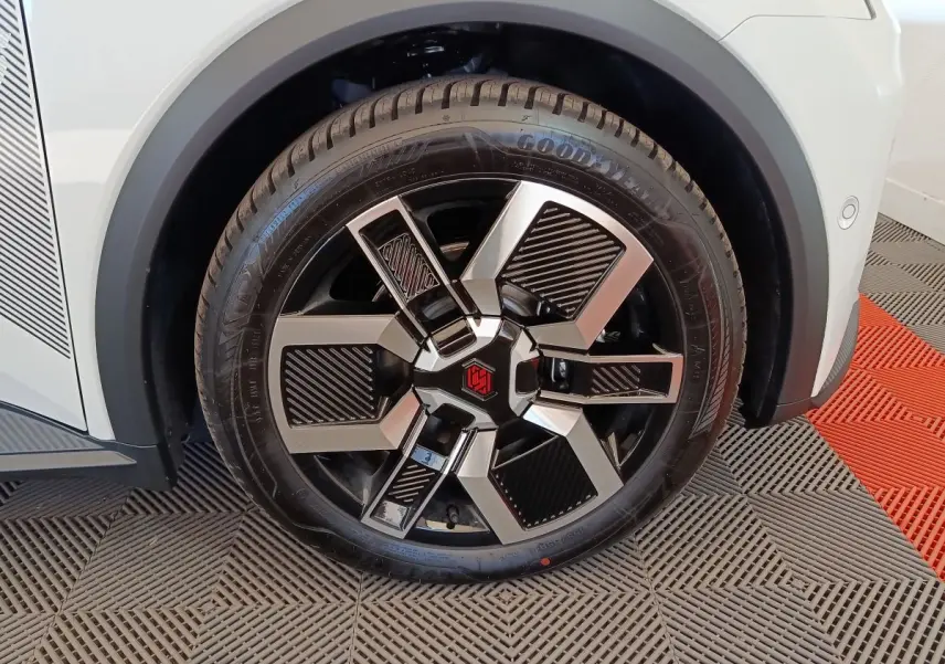 Gros plan sur la roue avant droite d'une Renault R5 Techno blanche, jante noire et argentée au design moderne.