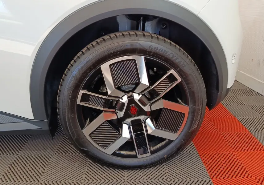 Gros plan sur la roue avant droite de la Renault R5 Techno blanche, avec jante noire et argentée au design géométrique.