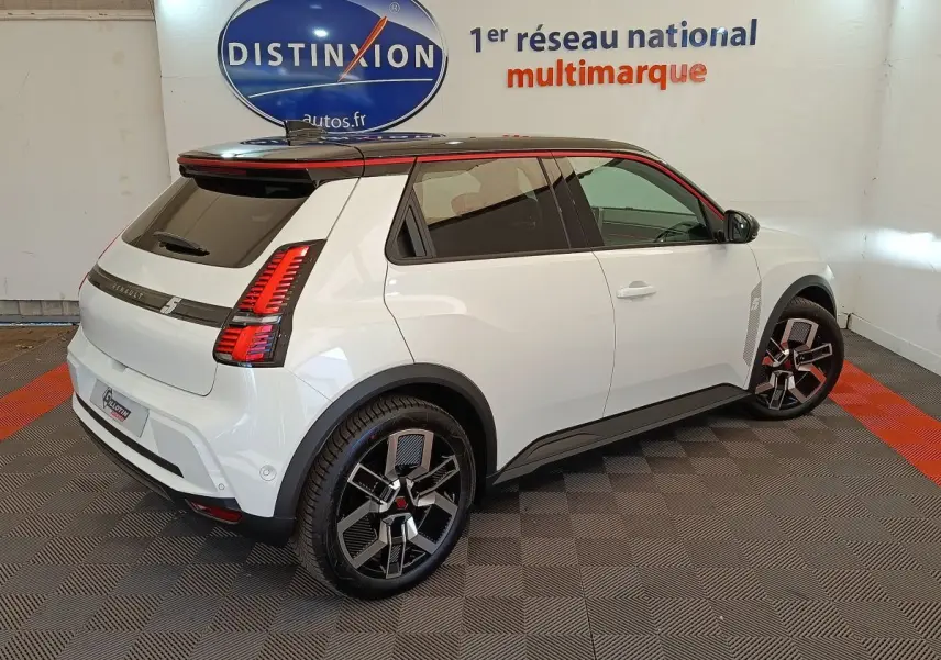 Vue 3/4 arrière droite d'une Renault R5 Techno blanche avec toit noir et jantes noires à motifs géométriques.