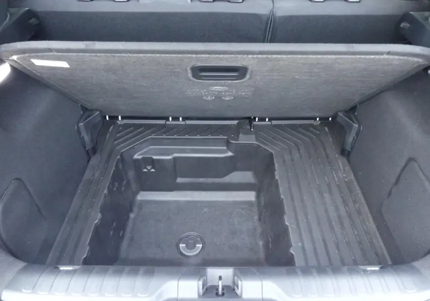 Vue plongeante sur le coffre ouvert du Ford Puma blanc, montrant le compartiment de rangement sous plancher.