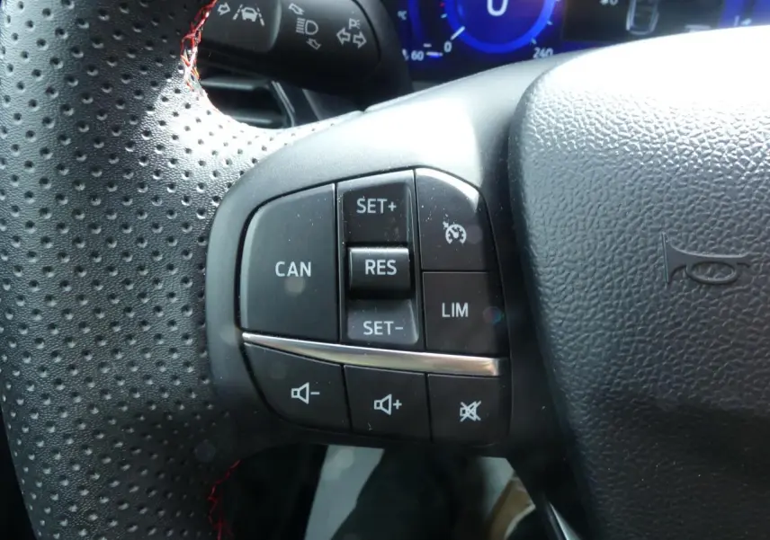 Gros plan sur les commandes de régulateur de vitesse et volume du volant perforé noir du Ford Puma blanc 2020 ST Line.