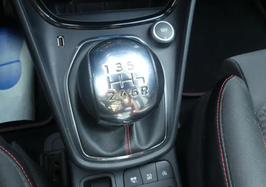 Gros plan sur levier de vitesses manuel chromé avec surpiqûres rouges sur sellerie noire du Ford Puma blanc ST Line.