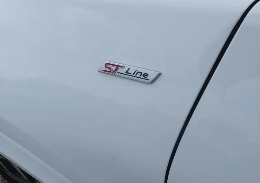Gros plan sur l'écusson ST-Line rouge et noir sur la carrosserie blanche d'une Ford Puma 2020.