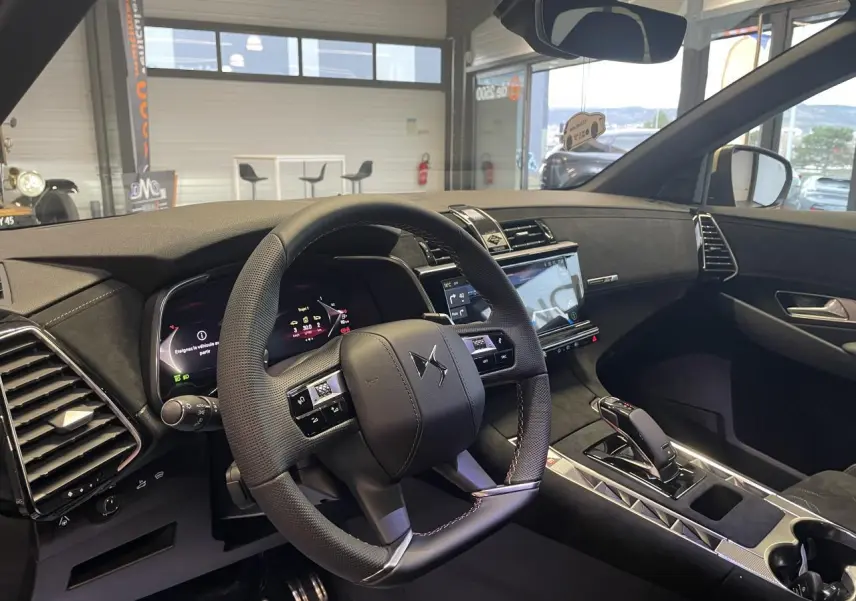 Vue intérieure avant droite du DS7 Crossback 2026, volant cuir perforé noir avec surpiqûres, tableau de bord et console centrale élégants.