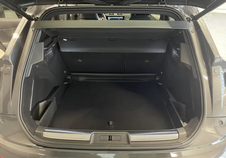 Coffre ouvert vu de l'arrière du DS7 Crossback gris titanium avec seuil de coffre chromé et intérieur noir.