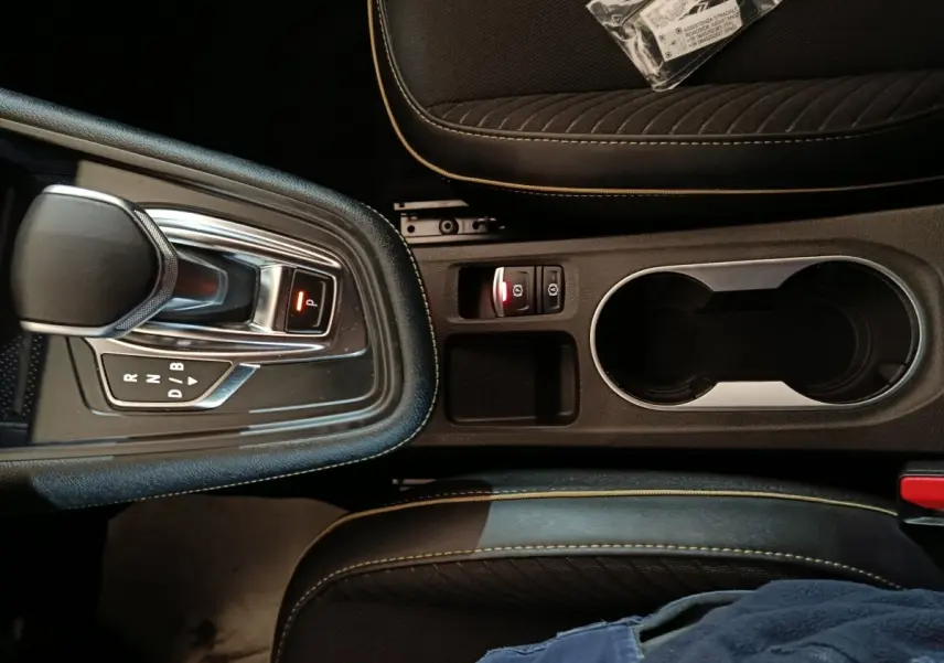 Vue plongeante sur la console centrale noire du Renault Symbioz avec levier de vitesse automatique et porte-gobelets.