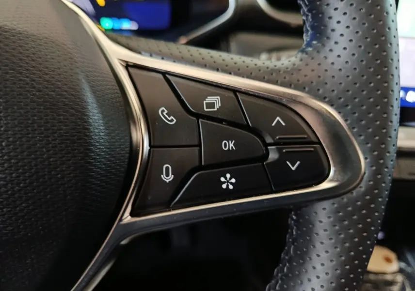 Gros plan sur les commandes multifonctions noires du volant perforé côté gauche du Renault Symbioz bleu 2025.