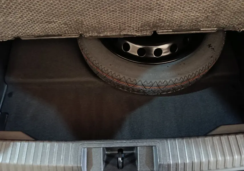 Vue rapprochée du coffre montrant la roue de secours sous la moquette, sans visibilité du véhicule Renault Symbioz.