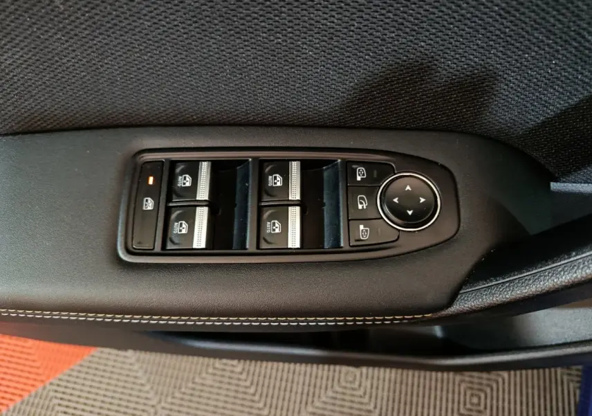 Détail des commandes des vitres et rétroviseurs sur la porte côté conducteur d'une Renault Symbioz bleu.