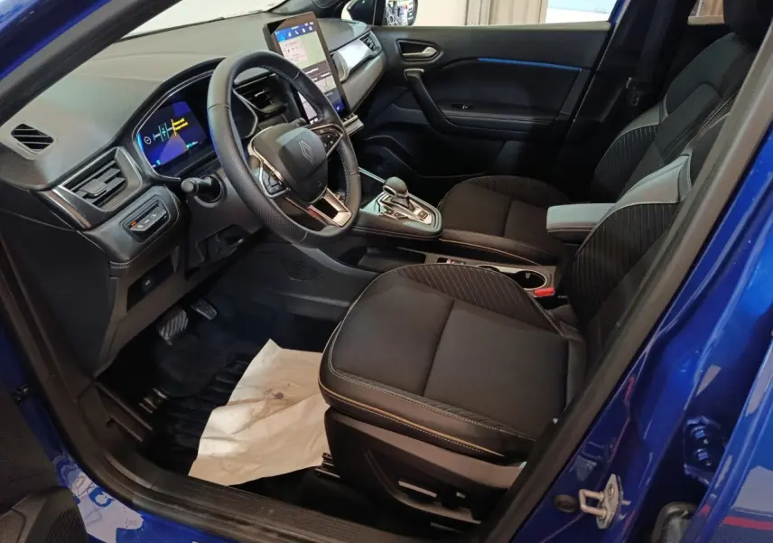 Vue intérieure côté conducteur de la Renault SYMBIOZ bleu, avec tableau de bord numérique et écran tactile central.