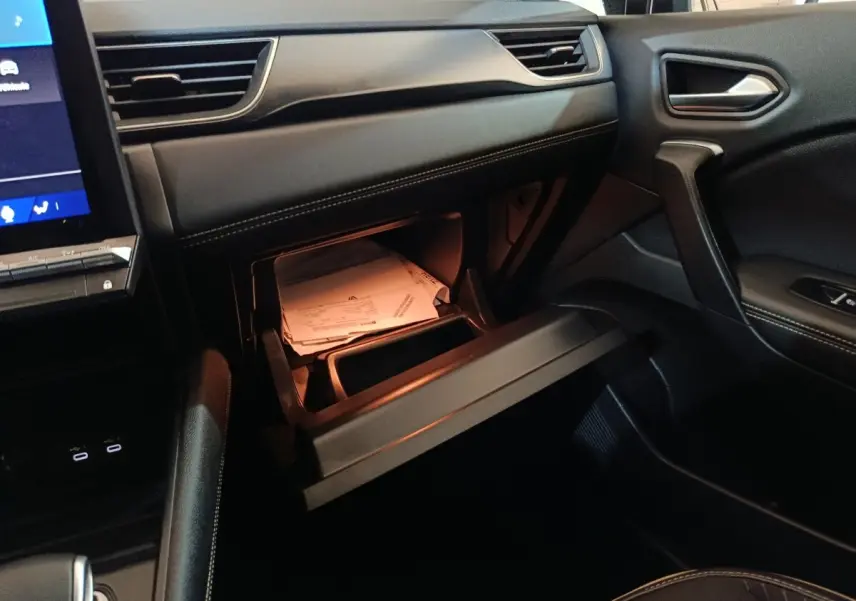 Vue intérieure côté passager du Renault Symbioz 2025 bleu, avec boîte à gants ouverte et documents visibles.