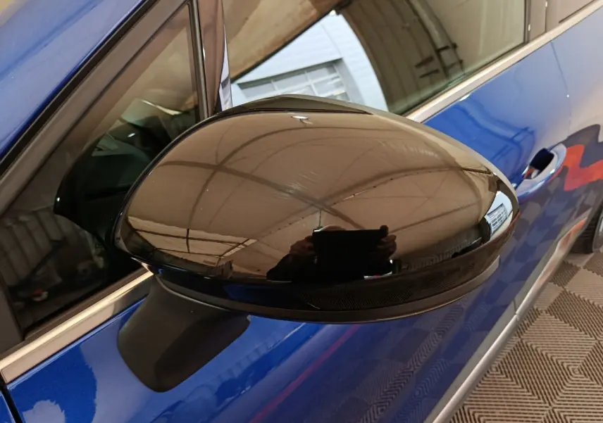 Rétroviseur noir brillant côté gauche sur Renault Symbioz bleu, vue rapprochée en angle avant.