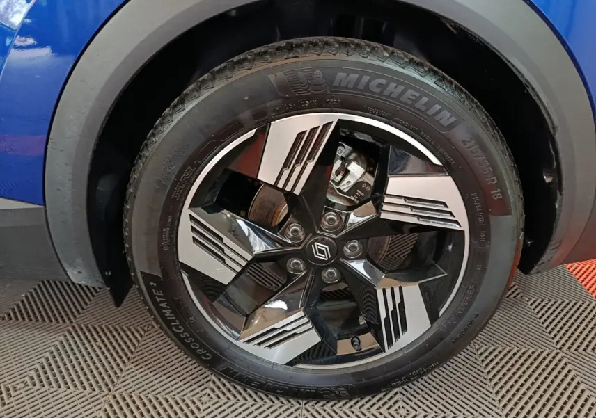 Gros plan sur la roue avant droite bleue du Renault Symbioz 2025 avec jante noire et argent au design géométrique.