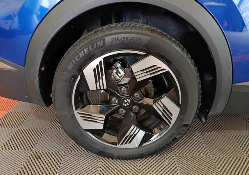 Gros plan sur la roue avant droite du Renault Symbioz bleu, jante alliage noire et argent avec logo Renault central.