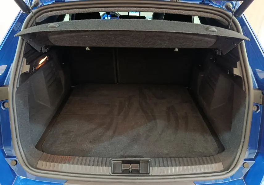Coffre ouvert vu de l'arrière d'une Renault Symbioz bleu, montrant un espace de chargement propre et spacieux.