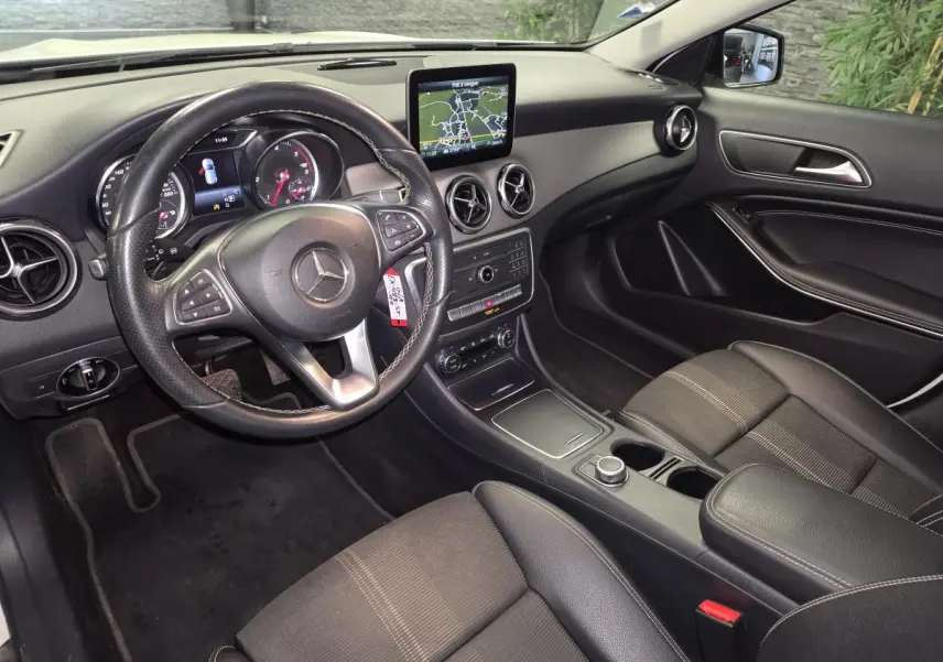 Vue intérieure côté conducteur du Mercedes GLA 220 d 2017, tableau de bord noir avec écran central et volant cuir multifonctions.