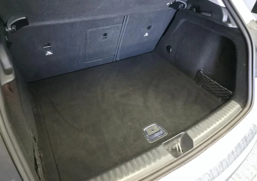 Coffre ouvert vu de l'arrière d'un Mercedes GLA blanc, montrant un espace de chargement propre et tapis noir.