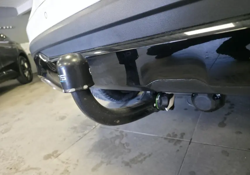 Gros plan sur l'attelage noir démontable sous le pare-chocs arrière blanc de la Mercedes GLA 220 d Sensation 4-Matic.