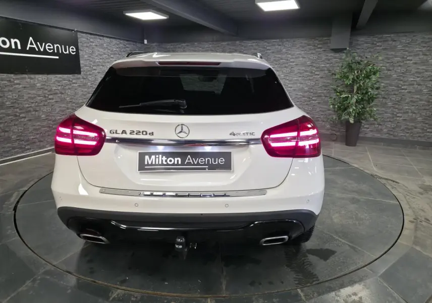 Vue arrière d'un Mercedes GLA 220 d blanc avec feux allumés, attelage démontable et logo 4MATIC visible.