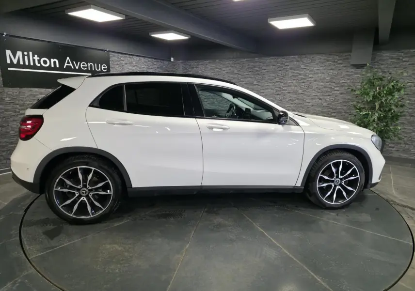 Vue profil côté gauche d'un Mercedes GLA blanc avec jantes alliage 19 pouces et vitres arrière surteintées.