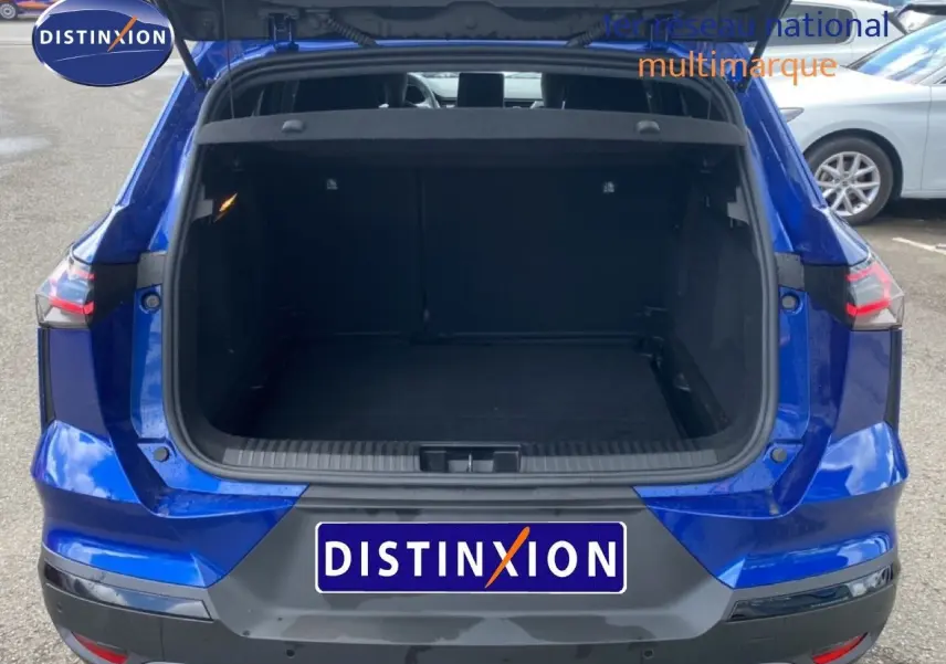 Vue arrière d'un Renault Symbioz E-Tech Full Hybrid 145ch Esprit Alpine bleu Iron Metal avec coffre ouvert sur parking.