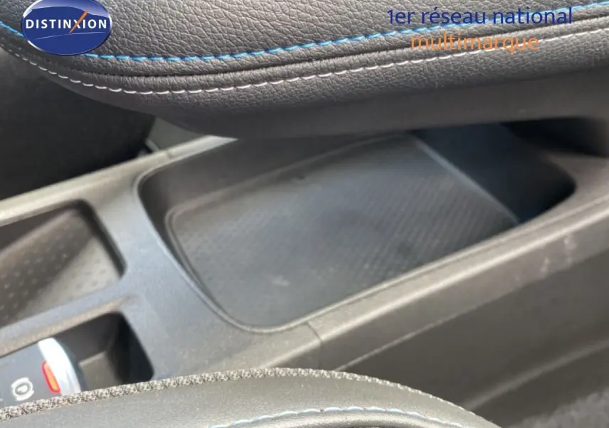 Gros plan sur la console centrale et accoudoir en cuir noir avec surpiqûres bleues du Renault Symbioz E-Tech hybride 2025.