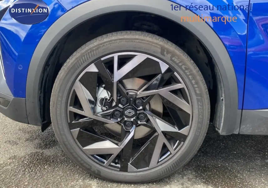 Gros plan sur la roue avant droite du Renault Symbioz bleu iron metal avec jante alliage au design géométrique.
