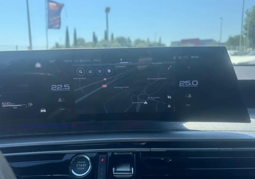 Tableau de bord numérique du Peugeot 5008 Hybrid 2025 avec écran central affichant la navigation et commandes climatisation.
