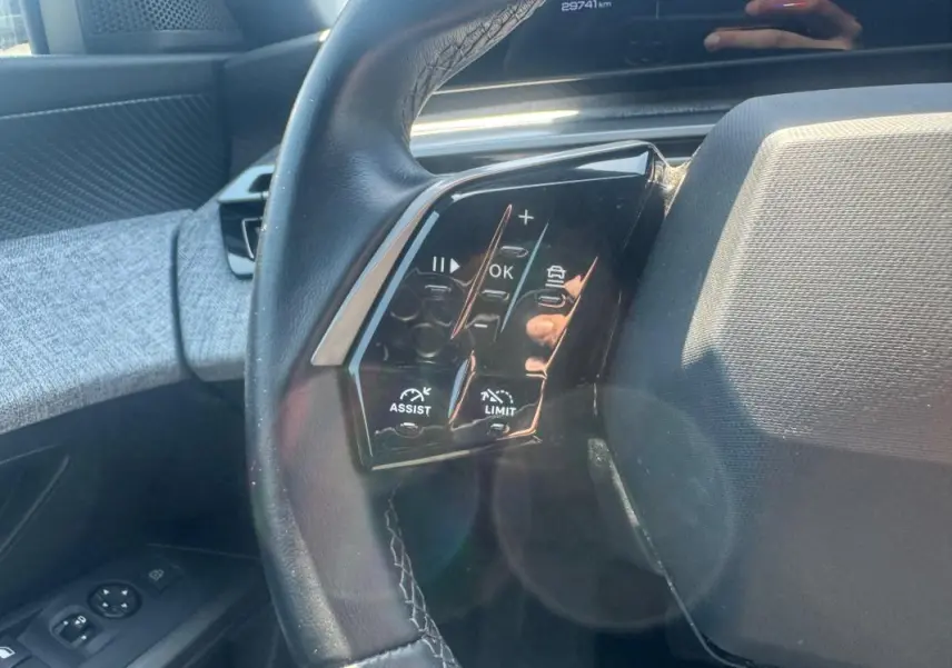 Gros plan sur le volant côté gauche du Peugeot 5008 gris 2025 Hybrid avec commandes d’assistance et limitation de vitesse.