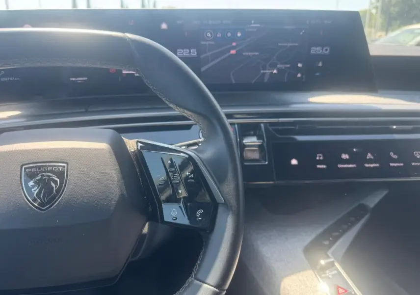 Vue rapprochée du tableau de bord et volant du Peugeot 5008 Hybrid gris 2025, avec écran tactile et commandes au volant.