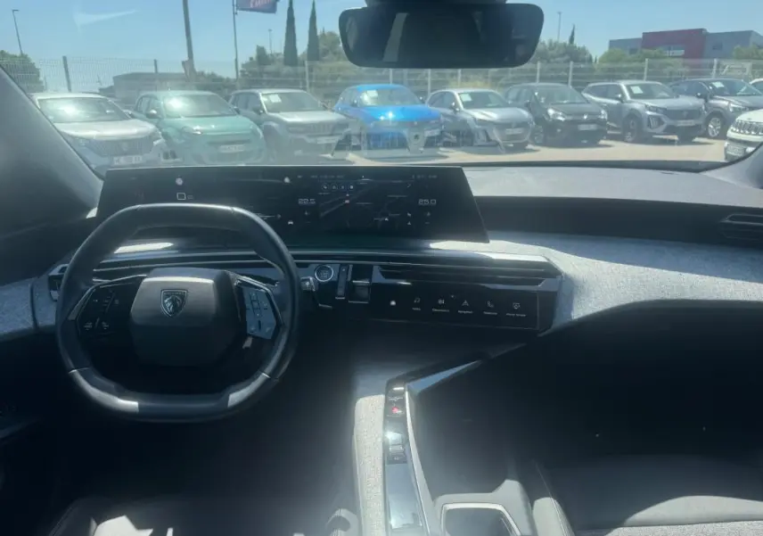 Vue intérieure avant du Peugeot 5008 Hybrid gris 2025, avec tableau de bord numérique et volant compact.