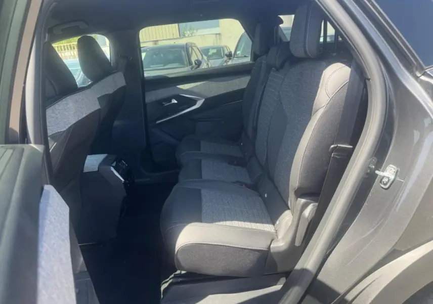 Vue intérieure côté droit des sièges arrière du Peugeot 5008 gris hybride 2025, avec sellerie tissu et cuir bicolore.