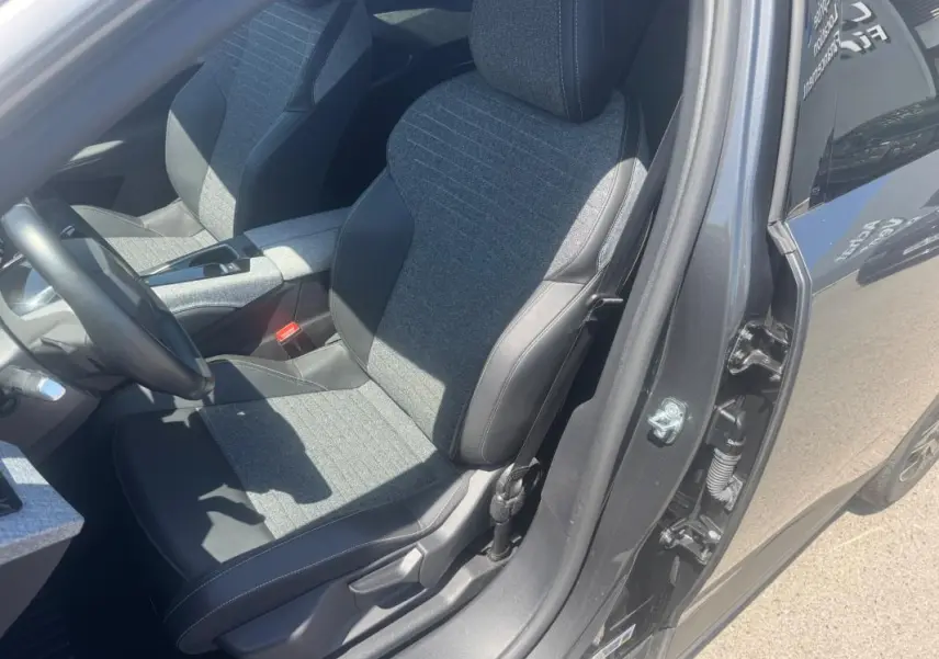 Vue intérieure côté conducteur du Peugeot 5008 Hybrid gris 2025, mettant en valeur les sièges tissu et cuir bicolores.