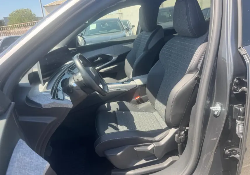 Vue intérieure côté conducteur du Peugeot 5008 Hybrid gris 2025, mettant en valeur les sièges bi-matière et le tableau de bord moderne.