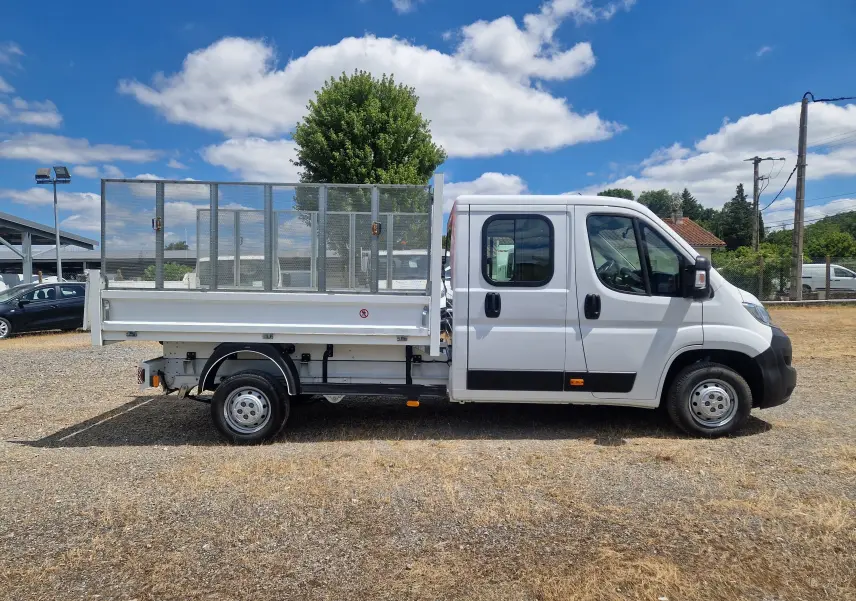 Vue de profil droit d'un Citroën Jumper blanc avec cabine double et benne 3m à ridelles grillagées.
