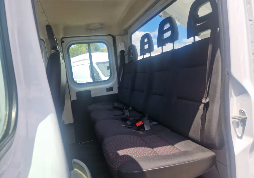 Vue intérieure côté droit des sièges arrière noirs avec appuie-têtes du Citroën Jumper blanc double cabine.