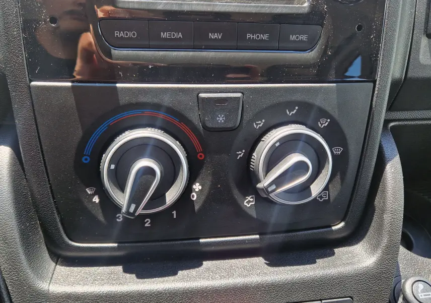Gros plan sur les commandes de climatisation et ventilation du tableau de bord du Citroën Jumper blanc, version L3 Benne 2021.